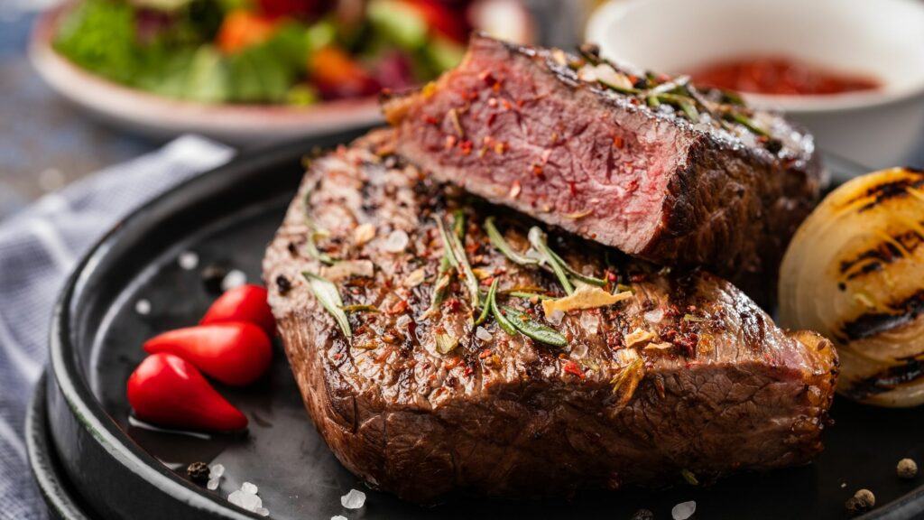 A perfectly grilled steak topped with sea salt an peppercorns