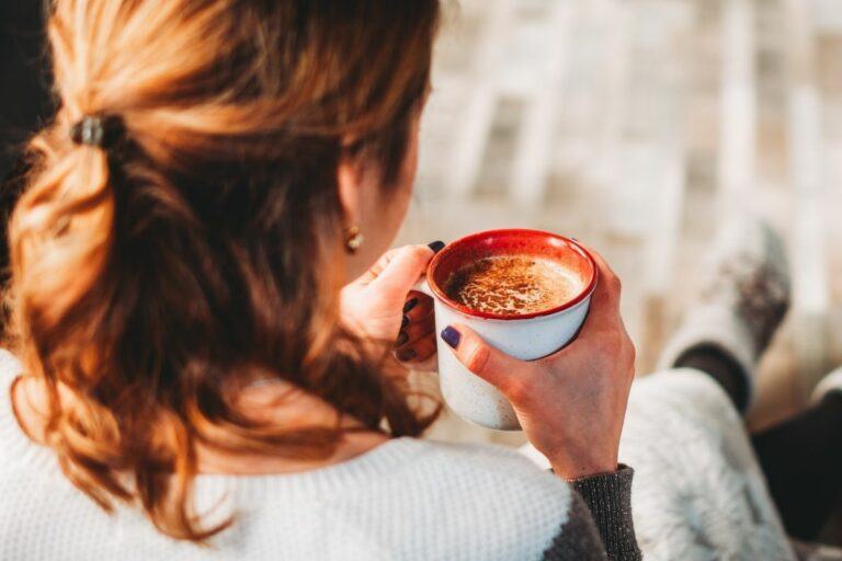 A woman in a warm sweater and slippers enjoying a cup of dairy-free bulletproof coffee